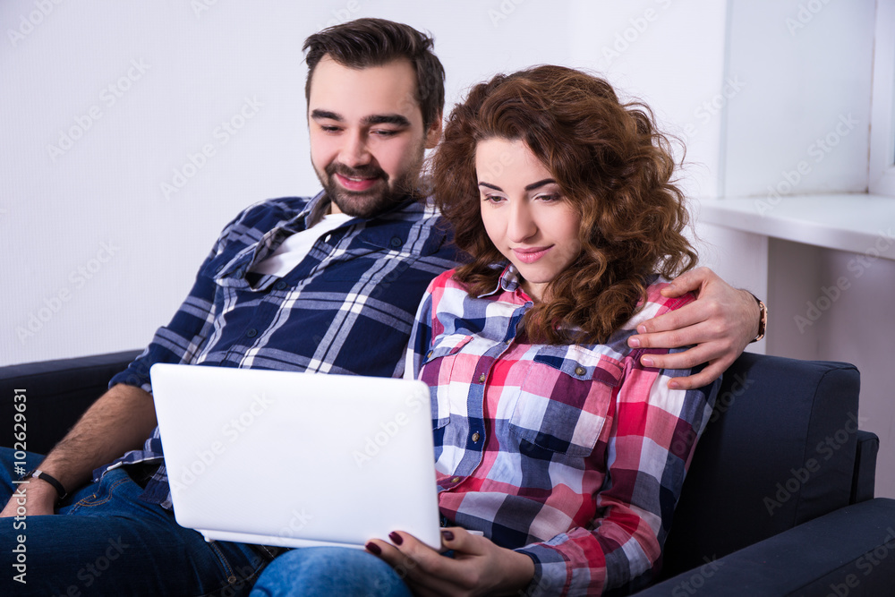 happy young couple with laptop on sofa