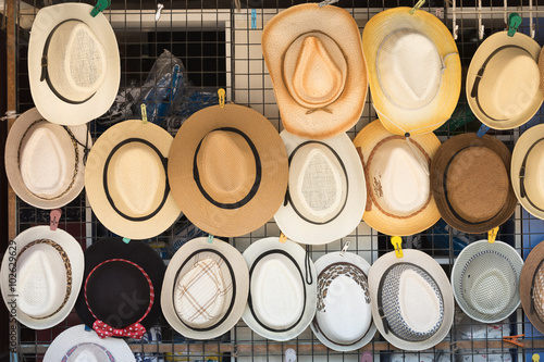 Straw hats for sale, hanging on a wall..