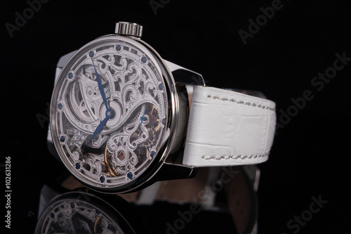 Metal case skeleton watches with blue hands and blue sapphires on leather strap front side view