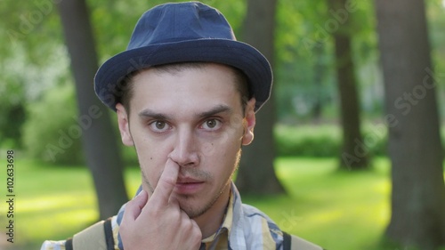 Portrait of boy in hat pick nose and then eat nose thing  . Outdoor. Summer photo