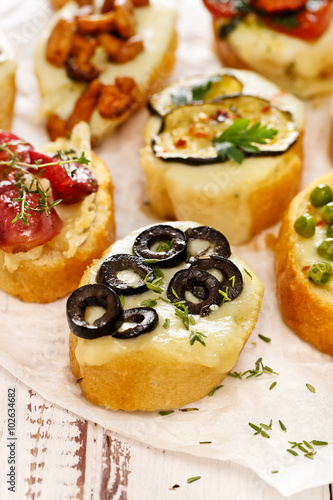 Crostini with addition of melted mozzarella cheese,  black olives and fresh thyme