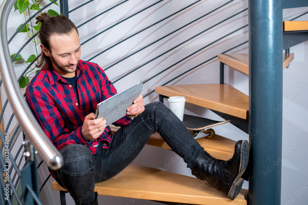 young sitting on stairs and using tablet PC young sitting on stairs and using tablet PC