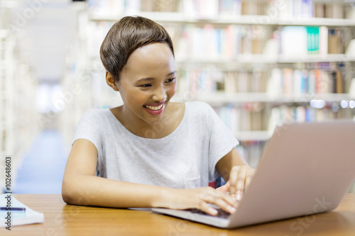 african college student with laptop sitting in library