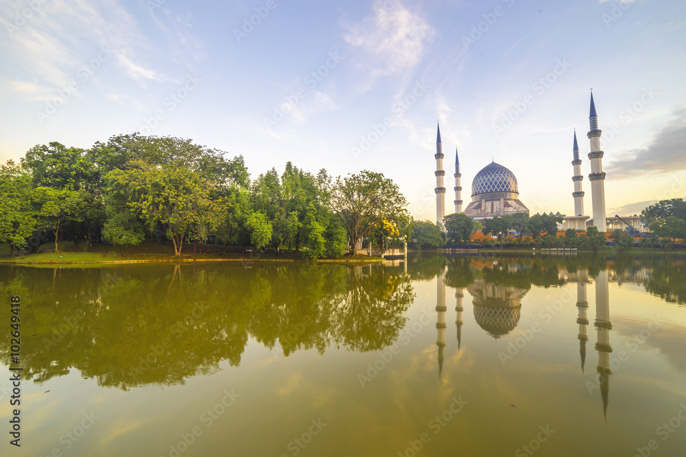 The Beautiful Sultan Salahuddin Abdul Aziz Shah Mosque (also known as the Blue Mosque) with nature sunrise lighting and reflection..