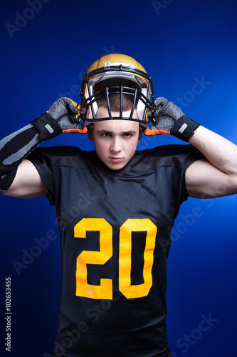 A player in american football with helmet on his head standing on blue background