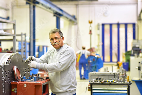 Obraz na plátně älterer Arbeiter montiert Getriebe in einer Fabrik // portrait industry workers