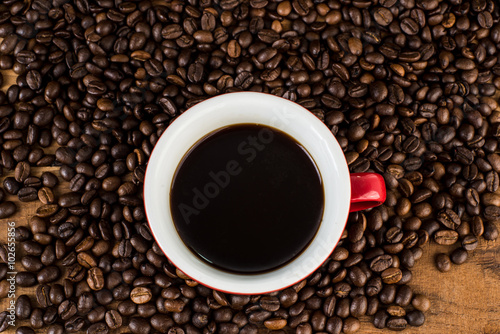 Cup of coffee and coffee beans on wooden table