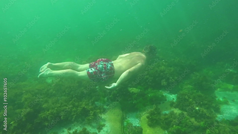 Man swimming underwater in slow motion, tropical sea in vacation time Man swimming underwater in slow motion, tropical sea in vacation time