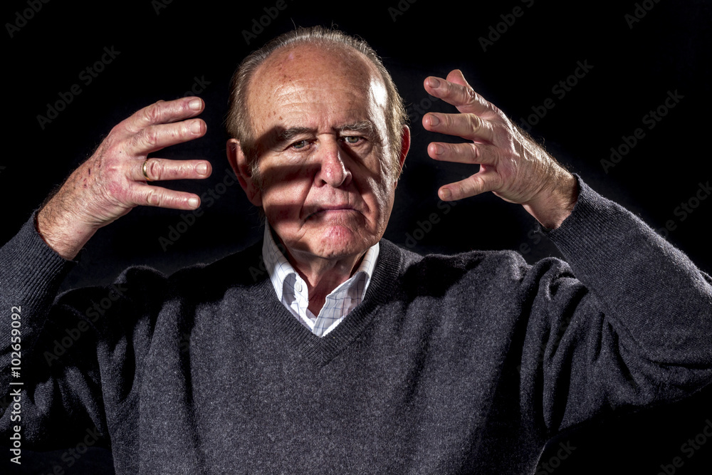 Senior man has an angry outburst, on black background