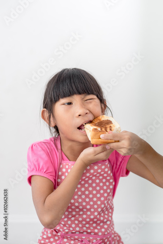 Asian girl eating bread at home.