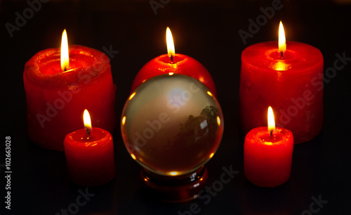 Crystal ball and five red candles burning