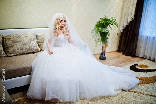 Curly blonde bride sitting and posing on the sofa