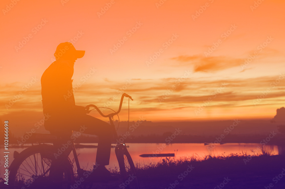 Cycler silhouette in sunrise against sun set cloudy sky