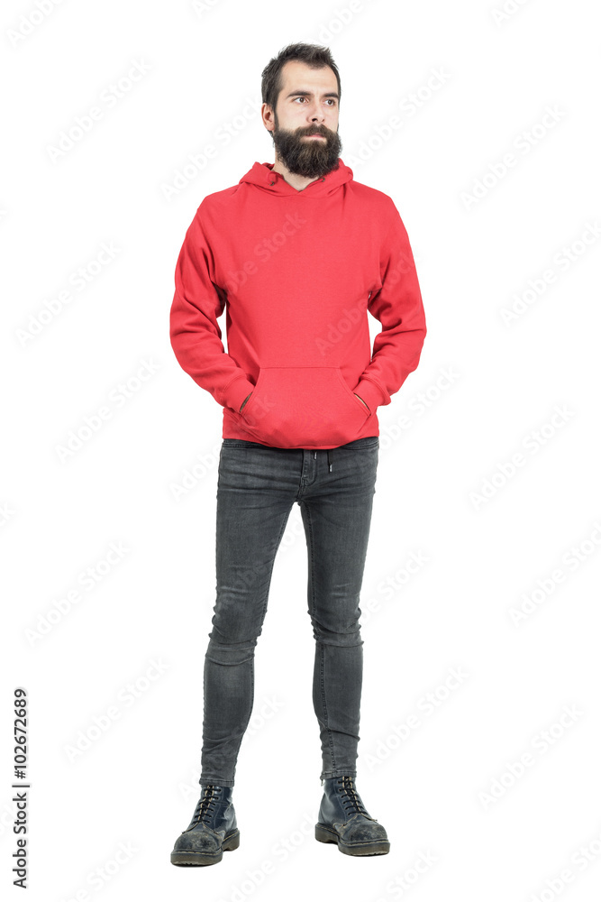 Serious young punker in red hooded sweatshirt looking away. Full body length portrait isolated over white studio background. Serious young punker in red hooded sweatshirt looking away. Full body length portrait isolated over white studio background.