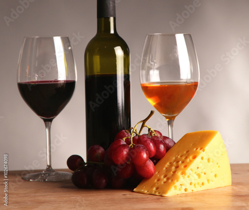 Refined still life of wine  cheese and grapes on wicker tray on wooden table