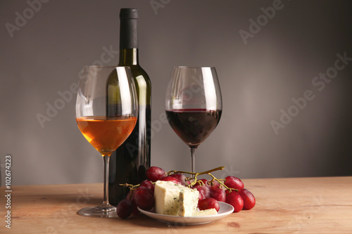 Refined still life of wine, cheese and grapes on wicker tray on wooden table