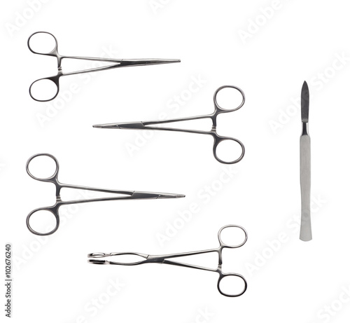 Close up of four stainless steel surgical forceps and scalpel