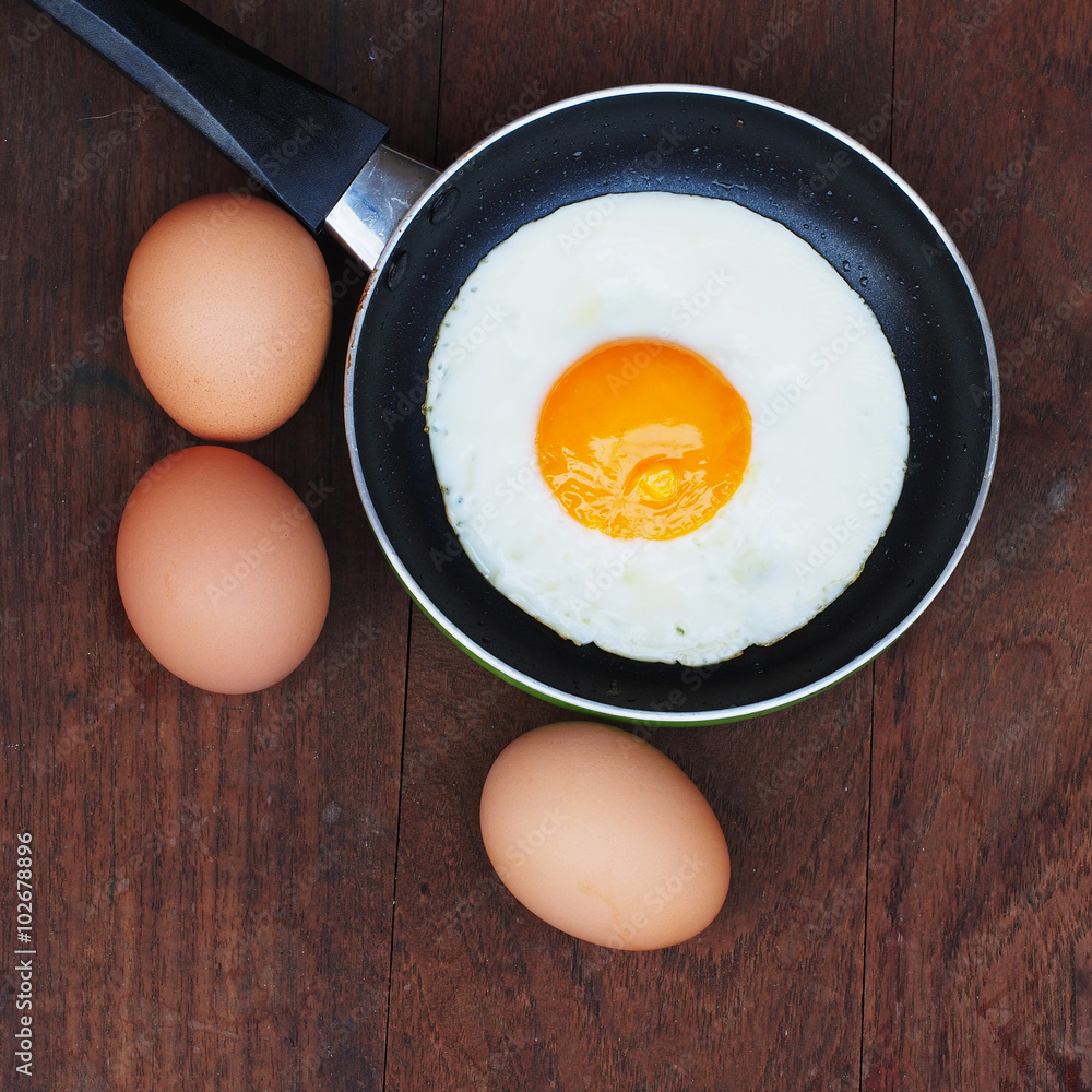 Fried eggs in a frying pan on wooden background Fried eggs in a frying pan on wooden background