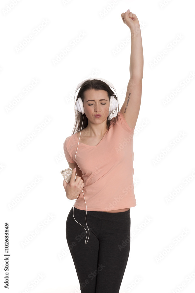 Junge Frau mit Kopfhörer und Handy hört Musik und streckt einen Arm nach oben Junge Frau mit Kopfhörer und Handy hört Musik und streckt einen Arm nach oben
