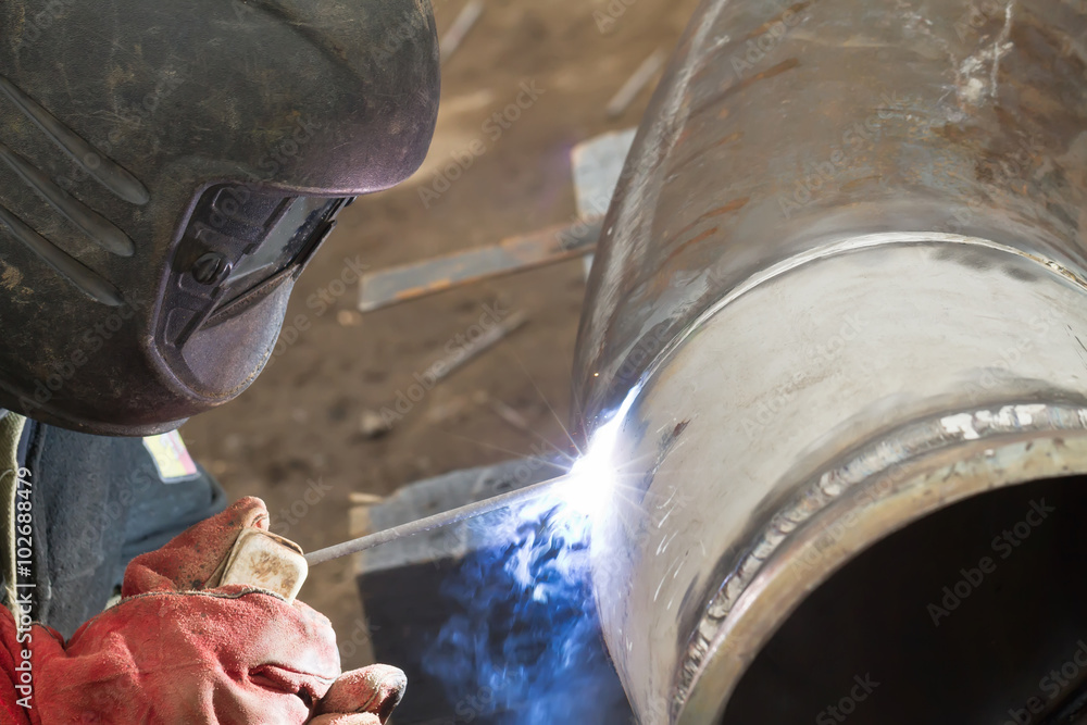 welder performs welding works on pipelines stainless steel