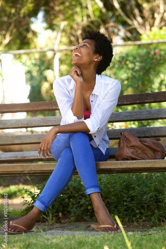 African woman laughing on a park bench