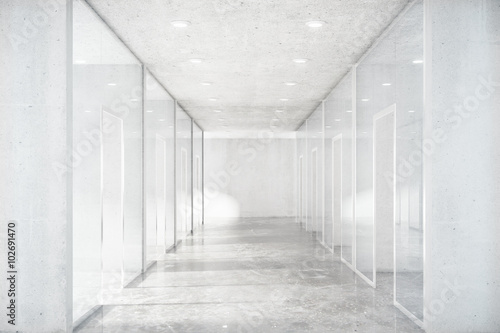 Long corridor with concrete floor and transparent walls in moder
