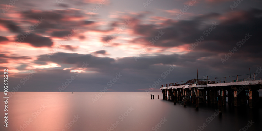 Cloudy sea sunrise with a jetty