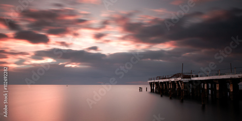 Cloudy sea sunrise with a jetty