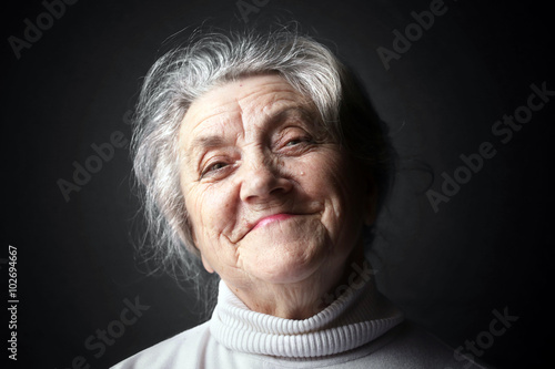 Happy granny portrait on a dark background 