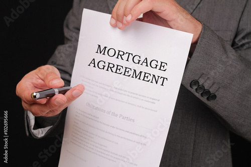 Mortgage agreement. Man offering a pen to sign  agreement close up. photo