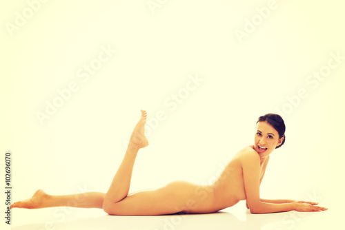 Nude woman lying on belly with one leg up