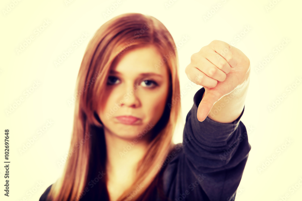 Young unhappy teenage woman showing thumb down Young unhappy teenage woman showing thumb down