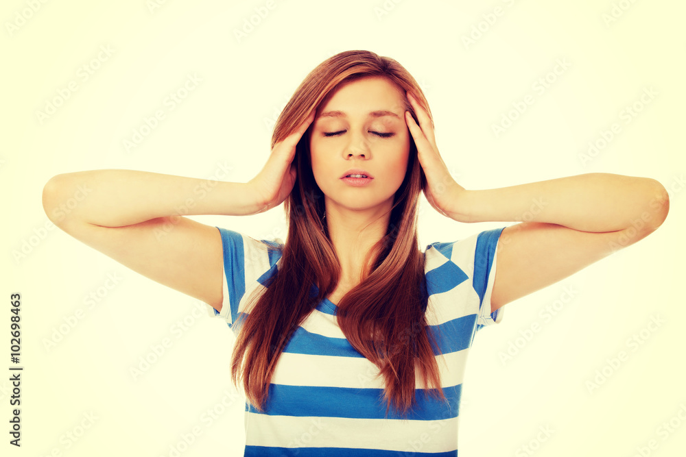 Teenage woman with headache holding her hand to the head