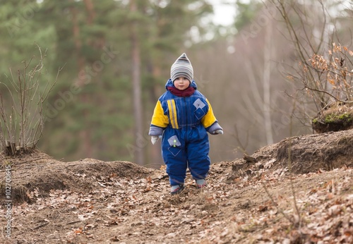 Little caucasian boy playing in forest at early spring
