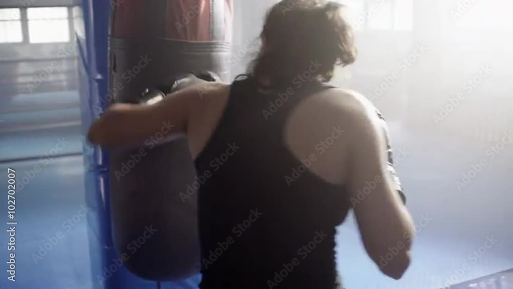 Young woman training with a punching bag in a boxing club. UHD, 4K.