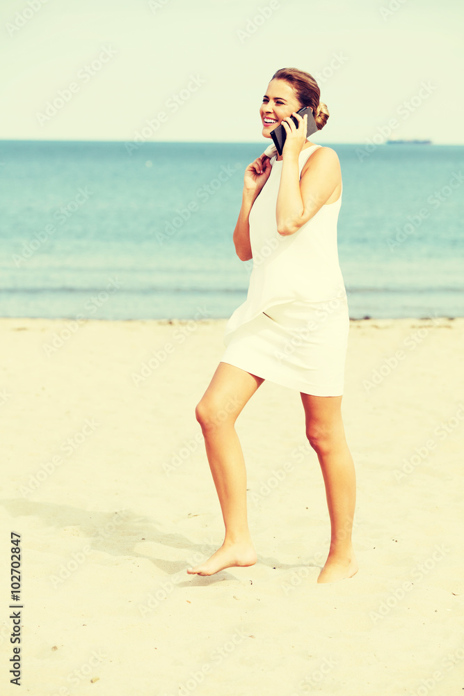 Young elegant beautiful woman talking on the phone on the beach Young elegant beautiful woman talking on the phone on the beach