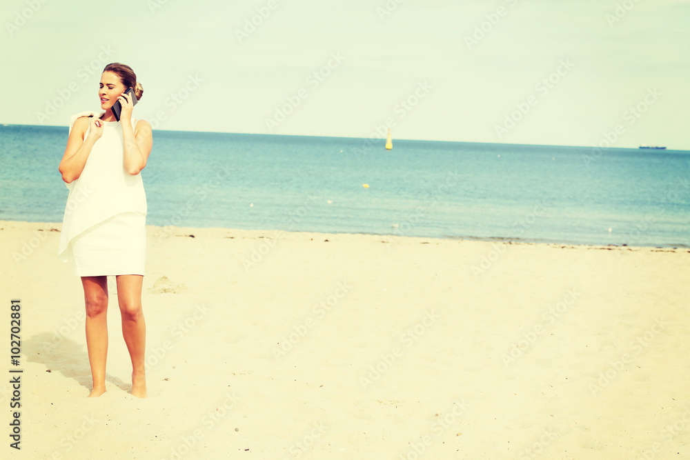 Young elegant beautiful woman talking on the phone on the beach Young elegant beautiful woman talking on the phone on the beach