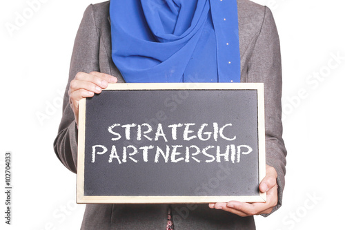 Businesswoman holding a chalk board written Strategic Partnership photo