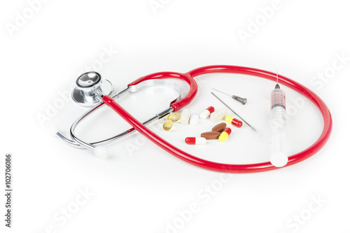 Red stethoscope with a hypodermic syringe and neddles on worktop