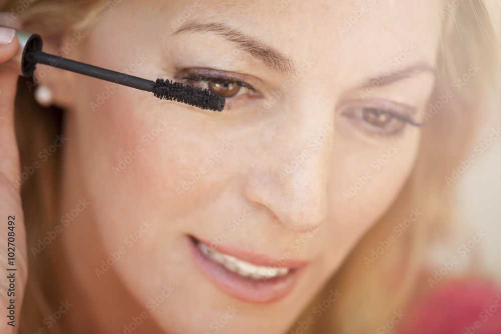 Portrait of a gorgeous female putting makeup on her eyes