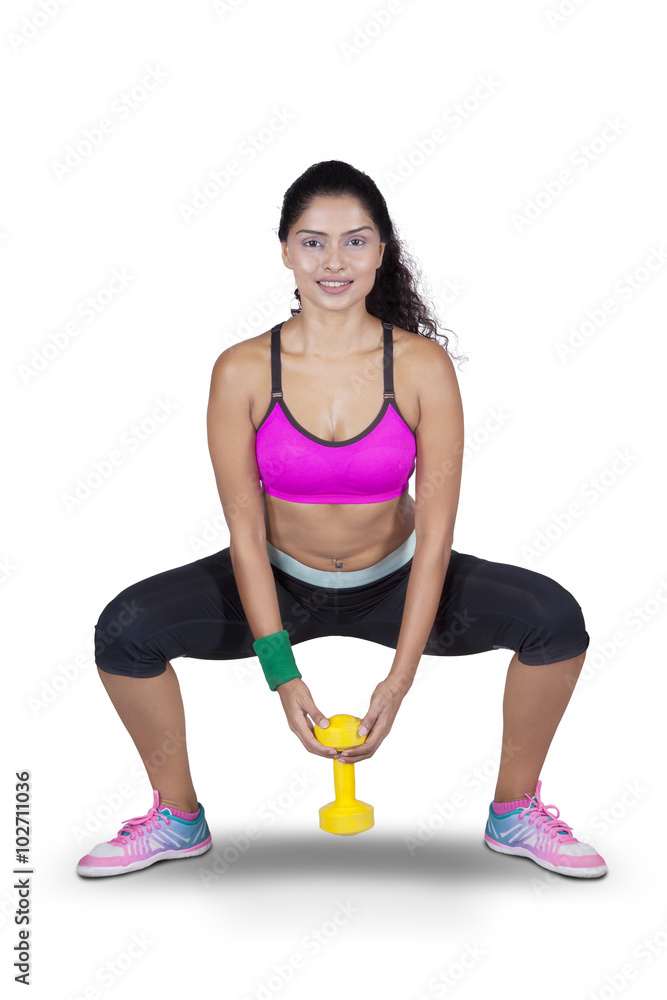Woman holding dumbbell while squatting foto de Stock Adobe Stock