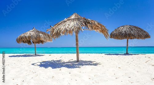 Beach Umbrellas made of palm leafs on exotic beach © PhotoSerg