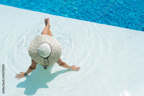 woman wearing a big hat relaxing at the swimming pool