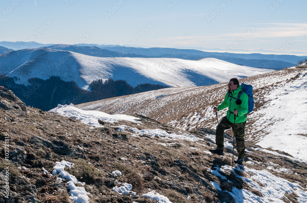 Male backpacker walking on mountain peak.