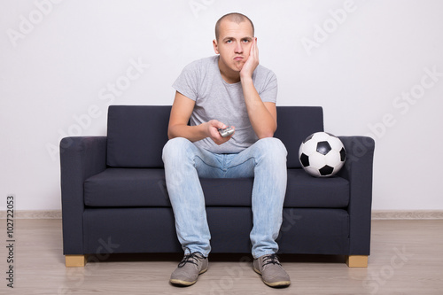 bored soccer fan watching game on tv photo