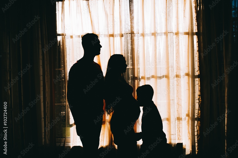 silhouette of a pregnant woman with her husband and child