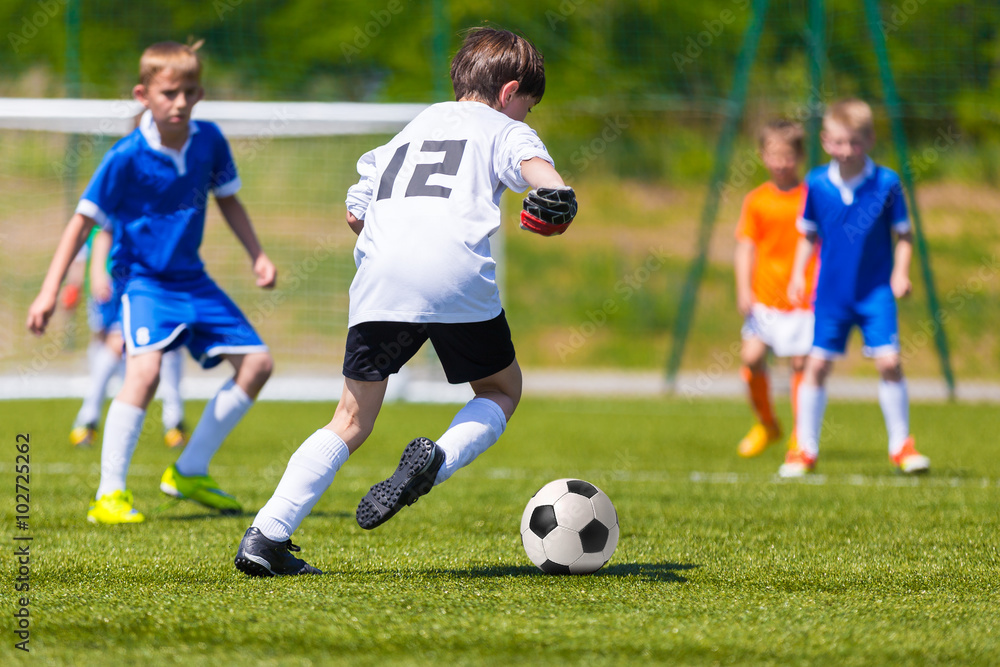 Young Boys Playing Soccer Football Match. Children Kicking Soccer Ball on a Sports Field. Youth football game and green Soccer Pitch in the Background.