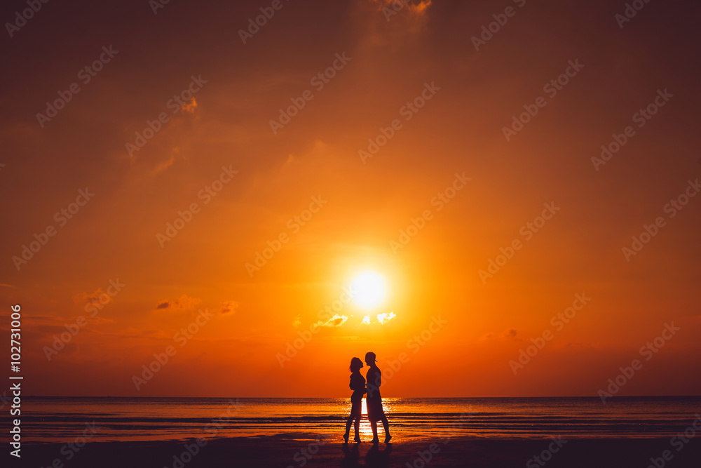 cute young beautiful couple posing on the beach at sunset, kissing his girlfriend softly on the forehead, hipster style, happily smiling in sunglasses on a tropical island,outdoor portrait, closee 