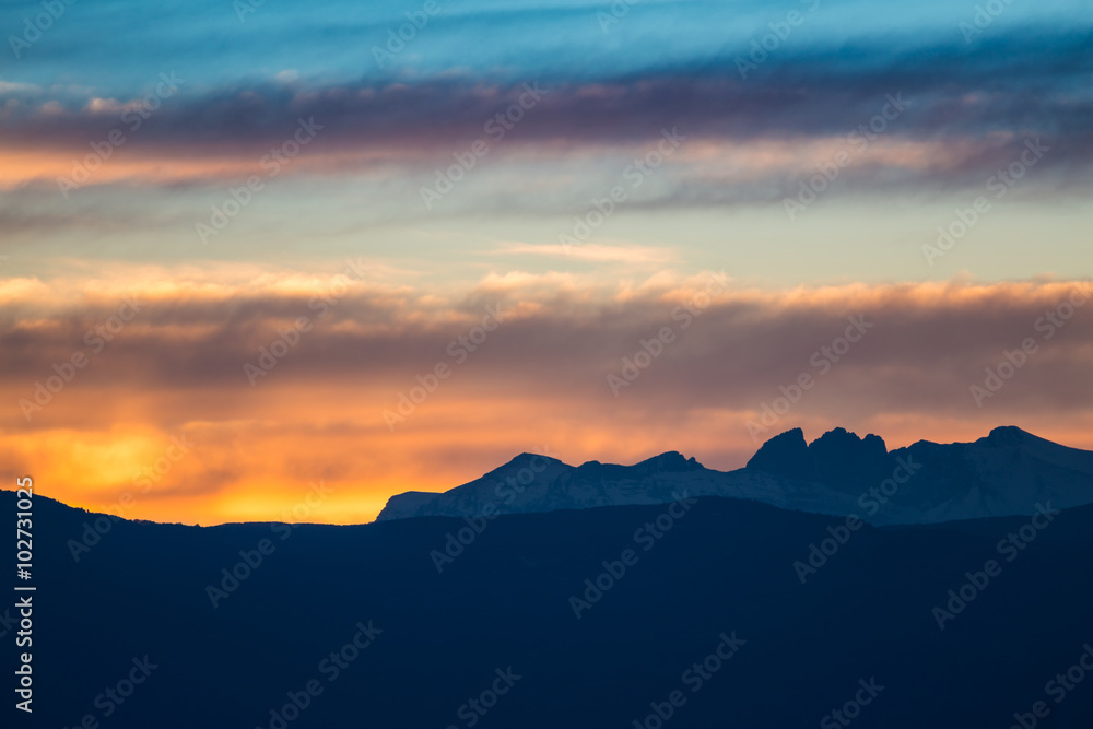 Sunset / sunrise with vivid colorful sky, clouds and mountains dark silhouettes.