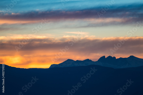 Sunset / sunrise with vivid colorful sky, clouds and mountains dark silhouettes.